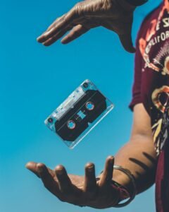 pexels-photo-1762578-1762578 A retro cassette tape floating between hands against a clear blue sky, evoking nostalgia.
