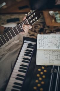 pexels-photo-3971985-3971985 Close-up view of a guitar and keyboard with sheet music, capturing a cozy indoor music session.